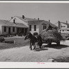 Lloyd Young, FSA (Farm Security Administration) client, hauling load of hay past the office and Community building of Plum Bayou Project, Arkansas (see general caption)