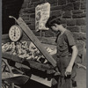 Teenage boy tending to a vegetable stand on the sidewalk