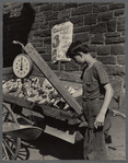 Teenage boy tending to a vegetable stand on the sidewalk