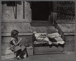 Young girl seated on a cardboard box on street sidewalk