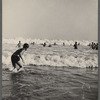 Beach scene with crowd of people catching waves in the ocean