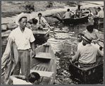 People in row boats, crowding the edge of a waterway