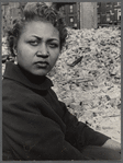 Portrait of a woman with sparkling earring, brick rubble and buildings in the background