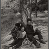 Three young children seated around the base of a tree