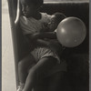 Young girl holds a toddler in her lap, and a balloon in hand 