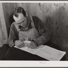 Mr. Verden Lee working on the farm family record book in his home. Transylvania Project, Louisiana
