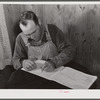 Mr. Verden Lee working on the farm family record book in his home. Transylvania Project, Louisiana