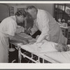 Dr. William J. Buck and nurse Anne Smock dressing infection on child's foot in clinic at Osceola migratory labor camp. Belle Glade, Florida