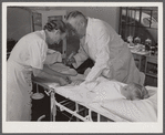 Dr. William J. Buck and nurse Anne Smock dressing infection on child's foot in clinic at Osceola migratory labor camp. Belle Glade, Florida