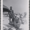 Three adults at beach next to beach umbrella