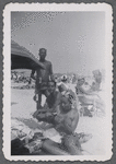 Three adults at beach next to beach umbrella