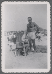 Man in swim trunks next to seated women