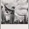 Camp member hanging out clothes outside of utility building which is equipped with complete laundry facilities and showers. Osceola migratory camp, Belle Glade, Florida
