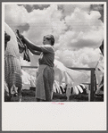 Camp member hanging out clothes outside of utility building which is equipped with complete laundry facilities and showers. Osceola migratory camp, Belle Glade, Florida