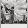 Camp member hanging out clothes outside of utility building which is equipped with complete laundry facilities and showers. Osceola migratory camp, Belle Glade, Florida