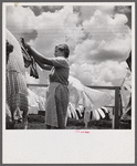 Camp member hanging out clothes outside of utility building which is equipped with complete laundry facilities and showers. Osceola migratory camp, Belle Glade, Florida