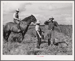 The waterboy brings one of the cooperative members a drink while he chops grass out of sugarcane field. The foreman, chosen by group from among own members, is on horse supervising work. Terrebonne Project, Schriever, Louisiana