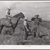 The waterboy brings one of the cooperative members a drink while he chops grass out of sugarcane field. The foreman, chosen by group from among own members, is on horse supervising work. Terrebonne Project, Schriever, Louisiana