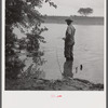 Farmer fishing in Cane River on Fourth of July. Near Natchitoches, Louisiana