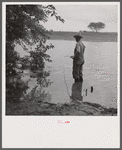 Farmer fishing in Cane River on Fourth of July. Near Natchitoches, Louisiana