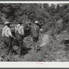Mountain people carrying a coffin up the creek bed to the family graveyard where it will be buried. This section is too isolated to have a formal funeral service immediately. Up South Fork of the Kentucky River, Kentucky.