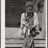 Mountaineer who reared his grandson in his home with the help of the neighbors. He had been crippled with arthritis most of his life. On the steps of a schoolhouse with his dog on South Fork of Kentucky River. Breathitt County, Kentucky.