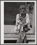 Mountaineer who reared his grandson in his home with the help of the neighbors. He had been crippled with arthritis most of his life. On the steps of a schoolhouse with his dog on South Fork of Kentucky River. Breathitt County, Kentucky.