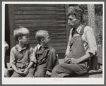 Mountaineer with his two grandsons whom he raised in his home with the help of the neighbors. He had been crippled with arthritis most of his life. On the steps of a schoolhouse on South Fork of Kentucky River. Breathitt County, Kentucky.