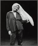 Publicity photograph of Whoopi Goldberg performing stand-up act  in leather pants, wearing a shirt on her head