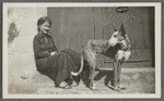 Woman seated in a doorway with a dog