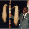 Mestre Didi standing with his work at the reception for his 1986 exhibition "Mestre Didi: An Afro-Brazilian Artist"