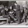 Fur buyer handing FSA (Farm Security Administration) supervisor his bid on the next lot of muskrats. The auction sale is being held on the porch of the community general store in Saint Bernard, Louisiana.