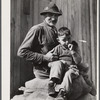 Spanish muskrat trapper and his grandson sitting on sacks of dried muskrat pelts, in front of their camp in the marshes. Delacroix Island, Saint Bernard Parish, Louisiana.