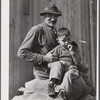Spanish muskrat trapper and his grandson sitting on sacks of dried muskrat pelts, in front of their camp in the marshes. Delacroix Island, Saint Bernard Parish, Louisiana.