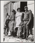 Spanish muskrat trapper with his father, his wife and their two children, in front of their camp in the marshland. Delacroix Island, Saint Bernard Parish, Louisiana.