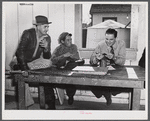 FSA (Farm Security Administration) Supervisor examining one of the trapper's furs during an auction sale held in a dance hall on Delacroix Island, Saint Bernard Parish, Louisiana.