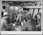 Spanish muskrat trappers drinking wine and playing "cache," a form of poker, in their camp in the marshes. Delacroix Island, Saint Bernard Parish, Louisiana.