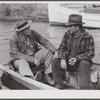 FSA (Farm Security Administration) supervisor talking to one of the trappers in his boat by one of the bayou marsh camps. Delacroix Island, Saint Bernard Parish, Louisiana.