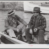 FSA (Farm Security Administration) supervisor talking to one of the trappers in his boat by one of the bayou marsh camps. Delacroix Island, Saint Bernard Parish, Louisiana.