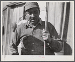 Spanish muskrat trapper by his marsh camp with reeds in his hand. These reeds are used to mark location of traps. Delacroix Island, Saint Bernard Parish, Louisiana.