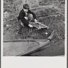 Spanish trapper's son setting the trap which he made to catch birds by his camp in the marshes near Delacroix Island, Louisiana.