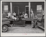 Construction workers on porch of local boarding house on highway near Fort Benning, Columbus, Georgia. They pay six dollars a week, several in a room. They are employed on Belair Construction job building defense housing project.