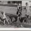 Children of Army men's families on Milstead Avenue playing in water in front of their new homes five miles outside of Columbus, Georgia.