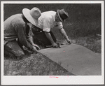 Fastening 16-mesh galvanized wire screen to battens before applying to open window frame. Screening demonstration. Charles County, La Plata, Maryland.