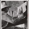 Cutting metal reinforcing for corners. Screen door construction demonstration. Charles County, La Plata, Maryland.