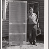 Door frame with screen wire assembled ready to fasten on hinge strip. Screening demonstration. Charles County, La Plata, Maryland.