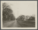 Flagpole (came from Oregon). Erected in 1899 (250th Anniversary of town). House on right of flagpole is Sam Miller's. East side Main St., north side of Dunemere Lane. East Hampton, East Hampton