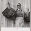 Spanish trapper's wife holding dried muskrat skins iIn front of their camp in the marshes near Delacroix Island, Louisiana.