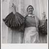 Spanish trapper's wife holding dried muskrat skins iIn front of their camp in the marshes near Delacroix Island, Louisiana.