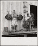Spanish trapper's wife and sister-in-law holding dried muskrat skins in front of their camp in the marshes near Delacroix Island, Louisiana.